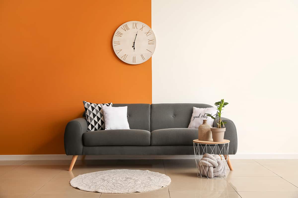 炭灰色的沙發配橙色的牆
